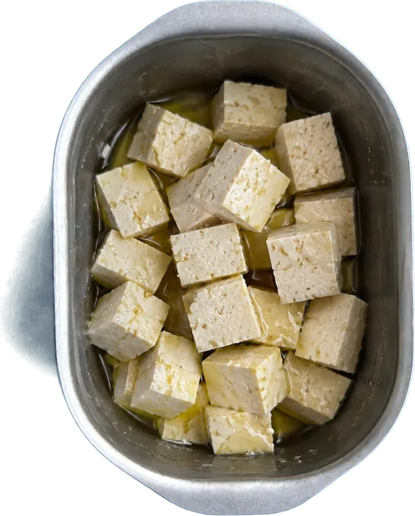 Nel secondo contenitore mettete 7.5 g di olio extravergine di oliva e 340 g di tofu compatto al naturale a dadini medi.